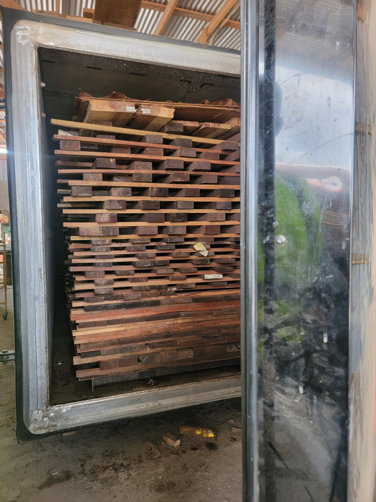 Hardwood boards stacked on spacers inside an open drying kiln