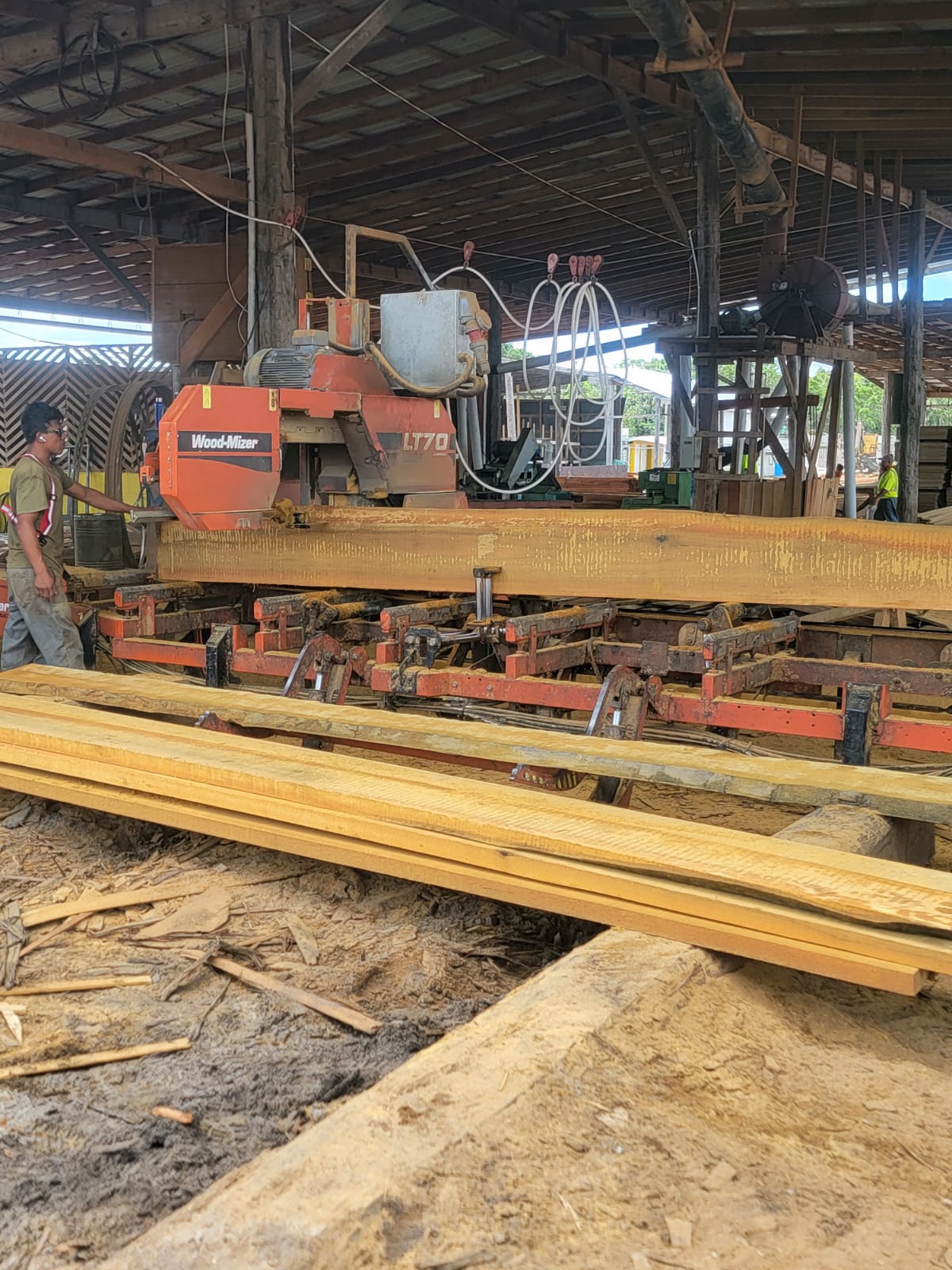 Operator running a hardwood beam through a horizontal band sawmill