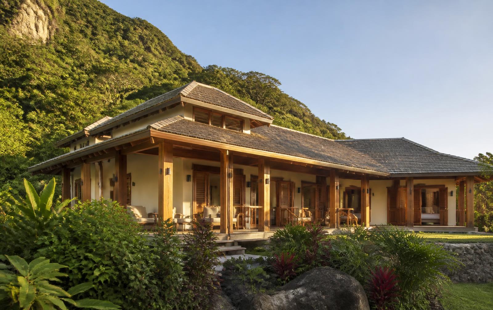 Completed hardwood home with shingle roof on a tropical hillside